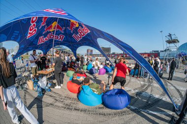 Kırmızı ve beyaz çizgili büyük mavi bir çadırın altında Kyiv 'de Sürüklenen Araba Festivali. Renkli fasulye torbaları üzerinde oturan insanlar kırmızı, mavi, yeşil, sarı. İki Individu Kyiv, Ukrayna 06-15-2025