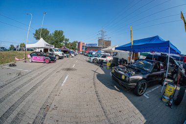 Kyiv Otomobil Sürükleme Festivali 'nde BMW arabası bir otoparkta bir etkinlik alanına dönüştü. Gökyüzü açık, canlı bir araba, insanlar etrafta yürüyor, dağınık çadır ve kulübeler, tr Kyiv, Ukrayna 06-15-2025