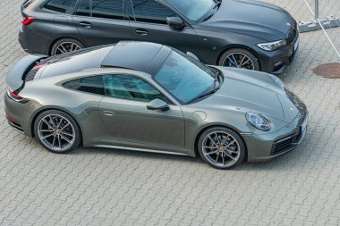 Üç araçlı çok katlı park yeri koyu gri SUV, açık mavi spor coupe, beyaz sedan beton yüzey, üstü kapalı ışıklandırma, gerçekçi stil Kyiv, Ukrayna 06-15-2025