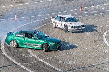 Kyiv 'de Araba Sürükleme Festivali, pistte dinamik sahne 3 BMW araba ortada yarış solda 2 beyaz, sağda 1 yeşil, Ukrayna 06-15-2025 tarafından kısmen gizlenmiş