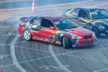 Kırmızı yarış BMW 70 Kyiv Araba Sürükleme Festivali, pistte dinamik sahne, takip eden arabalar mavi, sarı, pit lane, hafif ışıklandırma, rekabet, hareket Kyiv, Ukrayna 06-15-2025