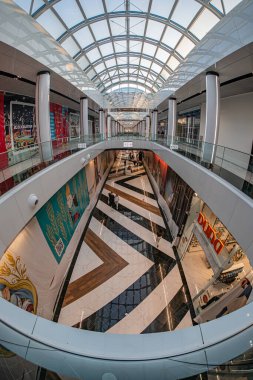 Modern, üç katlı atriyum alışveriş merkezi Kyiv 'deki Blockbuster Alışveriş Merkezi, geniş cam tavanlı, yürüyen merdivenlerde canlı sanat eserleri, dağınık parlak ışıklandırma, ge Kyiv, Ukrayna 06-15-2025