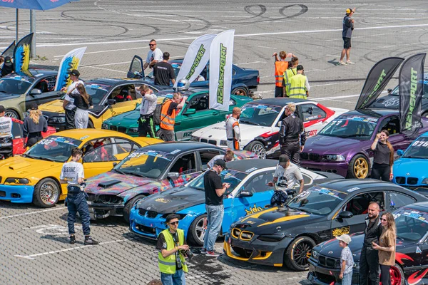 Kyiv 'deki araba fuarı, asfaltlı otoparkta çoklu yarış arabaları, iç işleri gösteren kaputlar, canlı renkler ve modeller, gün ışığını yansıtan parlak tasarımlar, sca Kyiv, Ukrayna 06-15-2025