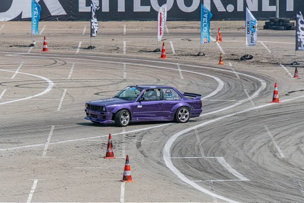Mor BMW araba toprak yolda sürükleniyor, turuncu koniler tarafından işaretlenmiş arka plandaki bulanık manzara hız ve hareketi Kyiv, Ukrayna 06-15-2025