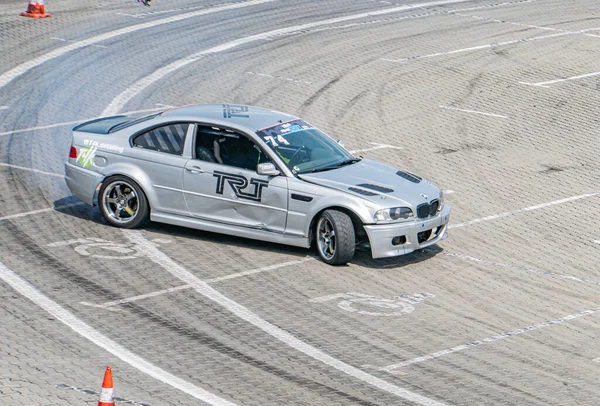 Kyiv Araba Sürüklenme Festivali sırasında iyi korunan bir pistte gümüş BMW yarış arabası TRT, sıkı bir viraj alıyor, seyrüsefer için turuncu koniler, e-Kyiv, Ukrayna 06-15-2025