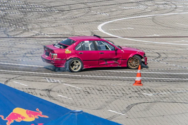 Yarış pistinin ortasında kırmızı renkli BMW arabası turuncu koni ile çizilmiş ve beyaz çizgilerle işaretlenmiş. Parlak doğal ışık, dinamik gölgeler Kyiv, Ukrayna 06-15-2025