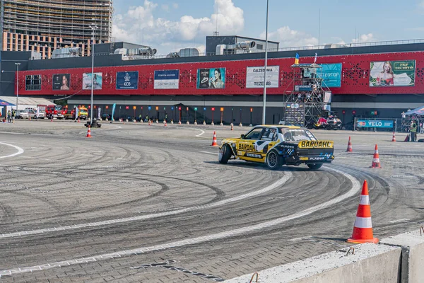 Beyaz ve sarı-siyah bir BMW 'nin turuncu kozalaklı gri bir pistte keskin bir sol dönüş yaptığı Kyiv, Ukrayna 06-15-2025