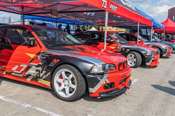 Kyiv 'de canlı kırmızı şemsiyeler, açık alan, doğal ışık, rastgele park etmiş arabalar, ca Kyiv, Ukrayna 06-15-2025' te siyah ve sarı çizgili kırmızı BMW yarış arabası.