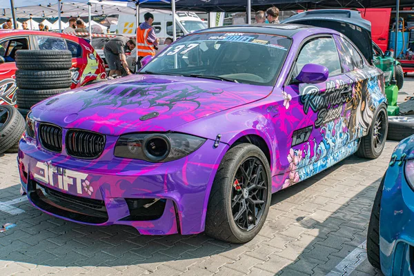 Kyiv Araba Sürükleme Festivali 'nde modifiye edilmiş BMW arabası, siyah aksanlı çarpıcı bir mor ve pembe renk şeması sergiliyor, büyük arka kanat spoiler, yan etekler, aerodyna Kyiv, Ukrayna 06-15-2025