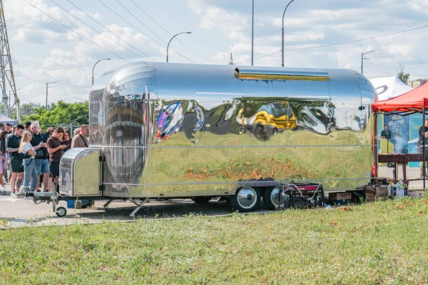 Açık havada güneşli bir gün. Parlak metal dış görünüşlü eski model bir karavan, muhtemelen bir karavan ya da seyyar ev olarak hizmet veriyor, merkezden yerleştirilmiş günlük giysiler, Kyiv, Ukrayna 06-15-2025