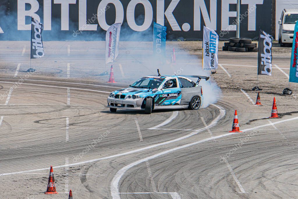 BMW car at Kyiv Car Drifting Festival on a circuit track, spinning tires sending smoke, track marshal in high-vis vest, natural light, paved and gravel areas, orange Kyiv, Ukraine 06-15-2025