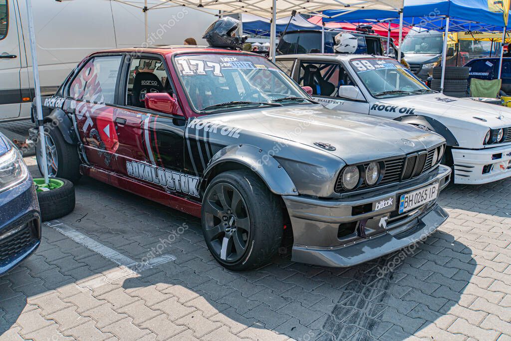 Kyiv Car Drifting Festival - Red and white BMW race car on tarmac, number 608, sponsor logos including Motorbase Performance, aerodynamic elements like rear wing and Kyiv, Ukraine 06-15-2025
