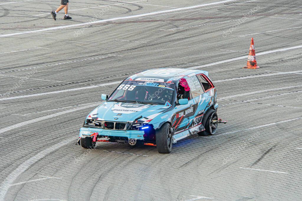 Blue BMW race car mid-drift at Kyiv Car Drifting Festival on a well-worn track during daylight, with visible scratches and rear wing Kyiv, Ukraine 06-15-2025