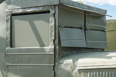 Açık havada park etmiş gri askeri kamyon, açık hava, yüksek açı, dikiz açısı, dairesel açıklıklar, ekipman deposu veya iletişim, metal saplar ve mandallar, pas, doğal aydınlatma koşulları, fuar