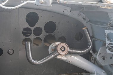 Görünür hasarlı uçaklar, çoklu kesikler ve petrol soğutucusuna bağlanan koyu metal bir borunun yakın çekim görüntüsü, açıkta kalan uçak bileşenlerini içeriyor.