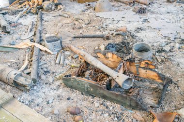 Harap olmuş dış alan askeri kutu, mühimmat, yanmış enkaz, metal enkaz, yanmış ahşap, sessiz toprak tonları, kararmış alanlar, insan yok, bulutlu aydınlatma