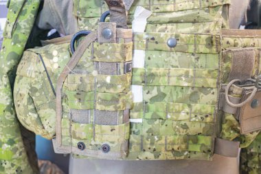 Ukrayna askeri üniformasına ait bir zeytin yeşili askeri yeleğin yakın çekimi, yamalar ve keselerle, muhtemelen açık havada, doğal aydınlatma, gizli stil