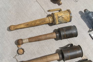 Açık gri arka planda beş antika eşya, eski bir projektör, iki paslı metal kutu, potansiyel bir fener, başka bir silindirik kutu ve kompakt bir cihaz.