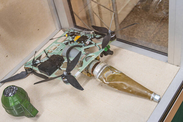 Деталь прозрачного витрины с украинским квадрокоптером на спине, показывающая внутренние компоненты Две прозрачные пластиковые бутылки частично скрыты на переднем плане одна пустая