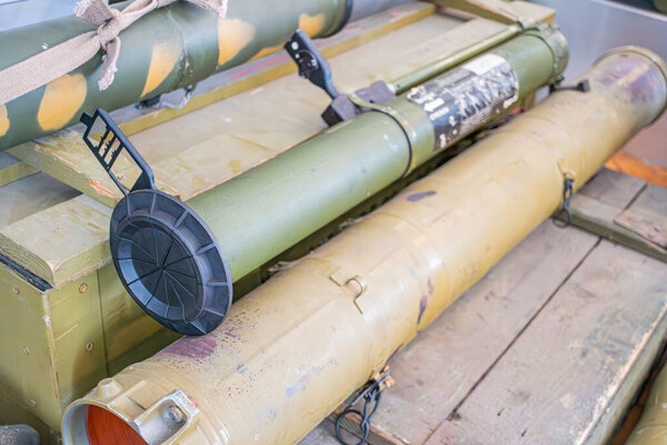 Древний танк с изношенной камуфляжем, несколько ракет прилагается, крытый деревянный пол, искусственное освещение, ржавые металлические поверхности