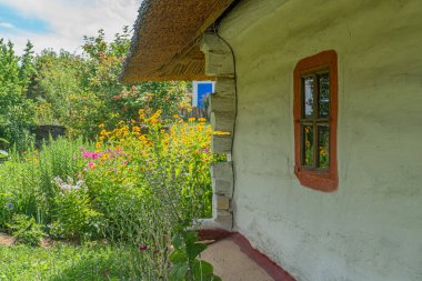 Orta Avrupa 'nın antik bir köyünde, kır evlerinin bahçesinde kırmızı pencere süslemeli, yemyeşil bitkilerin, çiçeklerin, çimenlerin, ağaçların, mavi gökyüzünün, yumuşak gün ışığının arasında yuva yapmış küçük bir kulübe.