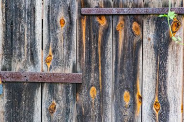 Ön, köşeli, paslı metal köşeleri olan, kahverengi ve siyah doğal tonlarda, dağınık ışık altında, muhtemelen kapalı ya da bulutlu, eski ahşap bir yapı.