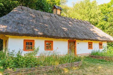 Kırsal, beyaz çiftlik evi, kırmızı süslemeli ve sazdan çatılı orman köyü manzaralı hiç kimse öğleden sonra fotorealistik tarzda doğal ışıklandırma sunmuyor.