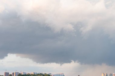 Şehir merkezi üzerinde fırtına yaklaşıyor, yüksek binalar yoğun, karanlık bulutlar yapılar içindeki yapay ışıklara zıt düşüyor. Gece vakti perspektifi yüksek görüş açısına sahip değil.