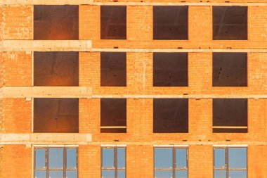 Modern bir şehirde inşaat halindeki kırmızı ışıklı, gri beton bir binanın yakın görüntüsü.