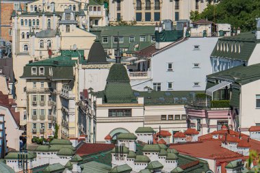 Tepenin tepesinden canlı, çok stil bir Avrupa şehri manzarası, kırmızı, yeşil, bej, çatıları ve daha aydınlık cepheleri olan gündüz binaları. İnsan yok, gerçekçi fotogra yok.