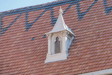 Eski bir Gotik Roma Katolik kilisesinin çatısına yakın çekim, küçük bir taret veya kubbeyi gösteriyor, büyük ihtimalle terakotta, kabarık desenli, karmaşık detaylarla beyaz, sıcak aydınlatma