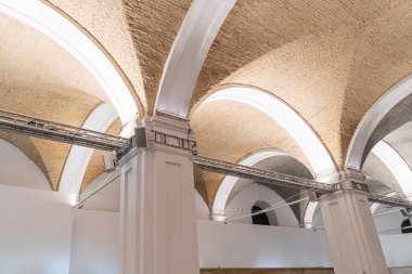 Eski bir Avrupa şehrinin boş, kemerli tavan odası, filtrelenmiş doğal ışıkla aydınlatılmış alan yatay kiriş ve desenli tuğla tavanı beyaz duvarlarla çelişiyor Docum.