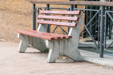 Şehir merkezinde, tuğla kaldırımda, yumuşak ışıklandırmanın altında, ahşap bir bankta, sessiz toprak tonlarının altında.