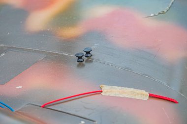 Sanayi bölgesinde üç objeye yakın çekim, karanlık merkezli ve açık kenarlı iki yuvarlak disk, muhtemelen daha uzun kırmızı silindirik bir nesne, natur altında düz bir yüzey üzerinde duruyor.