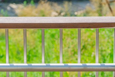 Dikey parmaklıklı metal korkuluklara yakın çekim, arka planda doğal bir arka plan üzerine kurulmuş, yumuşak ve dağınık ışıklandırma arka planda görülebilen bulutlu bir gün veya alacakaranlık yeşilliği önerir.