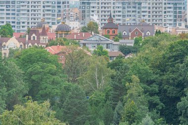 Kentsel ve doğal ortamlar arasındaki sınırı belirleyen yeşil ağaçlara karşı yerleşim ve karışık mimari yapıya sahip Kyiv şehrinin manzarası