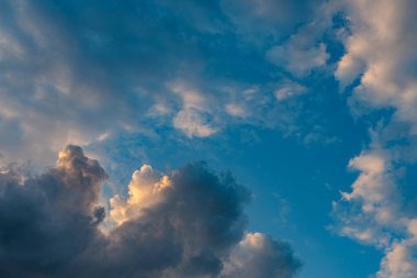 Dağıtılmış, kabarık, beyaz ve grimsi bulutlar yer seviyesinden canlı mavi gökyüzüne karşı