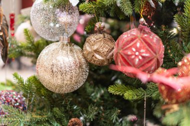 Canlı bir Noel ağacı, renkli küresel süslemelerle süslenmiş pembe, altın, beyaz etiketlerle süslenmiş ağaç yemyeşil iğnelerle kaplıdır ve her iki Noel için de şenlikli bir ortam sunar.