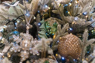 Süslü, ağırlıklı olarak beyaz ve gümüşi bir Noel ağacının yer aldığı profesyonel bir görüntü bulanık bir zemin üzerinde birçok ışıkla aydınlatılır ve altınla süslenir.