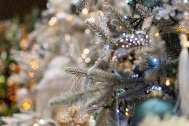 Çeşitli süslemeler, çam kozalakları, altın takılar ve mavi boncuklarla süslenmiş bir Noel ağacının yakın çekimi.