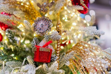 Altınla, gümüşle ve kırmızı süslemelerle süslenmiş Noel ağacı, sessiz arka planda, sıcak ışık altında