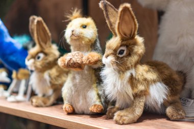 Boyut, renk ve detay olarak üç pelüş tavşan oyuncağı, bir rafta simetrik olarak dizilmiş yumuşak dokular, hatta renklendirici Kyiv, Ukrayna - 12 Kasım 2025