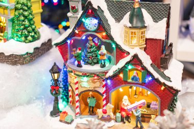 Kırmızı ve yeşil çatılı bir ev, karlı bir üs, etkileşen figürler, neşeli ışıklandırma ve Ukrayna 'nın Noel ruhunu anımsatan detaylarla dolu minyatür bir Noel köyü sahnesi - 12 Kasım 2025