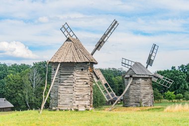Antik Orta Avrupa kırsal köyü, iki manzaralı yel değirmeni - geniş yelkenli ön perspektif daha düşük açılı - aşınmış ahşap merdiven ve merdiven Rustik yapısı, çimenli su