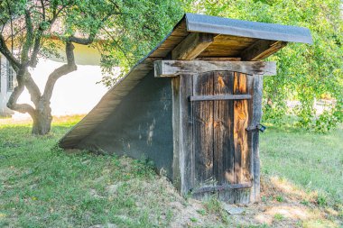 Eski bir Orta Avrupa köyü. Ahşap ahşap, eğimli çatı, ağaçların arasından süzülen güneş ışığı.