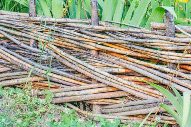Orta Avrupa 'nın antik bir köyünde, doğal renk ve doku değişiklikleriyle ince dallardan yapılmış ahşap çit yemyeşil ve düz olmayan küçük topraklara karşı kurulmuş.