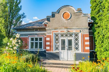 Gri, beyaz, kırmızı tuğlalı ev dekoratif pencereli ve dairesel motifli, muhtemelen düz çatıdaki güneş panelleri, yemyeşil bahçe, gün ışığı, Antik Orta Avrupa köyü