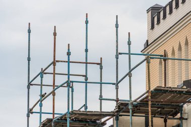 İnşaat malzemeleri ve inşaat halindeki çok katlı bina ile sürmekte olan kentsel bir inşaatın yapı iskelesi gündüz vakti bulutlu aydınlatma altında