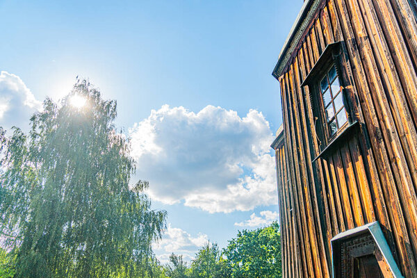 Древняя деревянная православная церковь в среднеевропейской деревне, под солнечным небом с контрастным зеленым деревом Выветриваемым лесом, открытыми ставнями, низким солнечным светом, травянистым окружением, без людей и текстов На