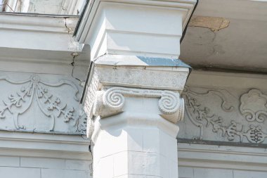 Şehir merkezindeki neoklasik sütun detaylarına yakın plan, çiçek yapraklarının oymalarını vurguluyor. Yukarıdan alınan görüntü c 'nin dikeyliğini ve dekoratif unsurlarını gösteriyor.